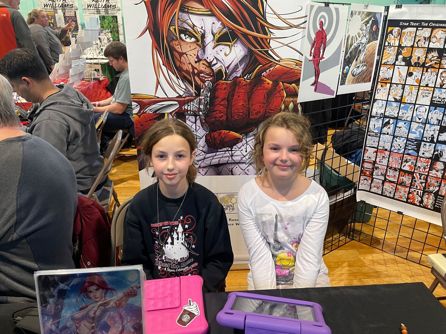 Melanie Russertt, 11, left, isn’t a big fan of comics, but her sister Kaylee, 9, has a 15-way tie for her favorite superhero. They both say that their favorite part of HurriCon is supporting their dad, Phil, who created an original comic series.