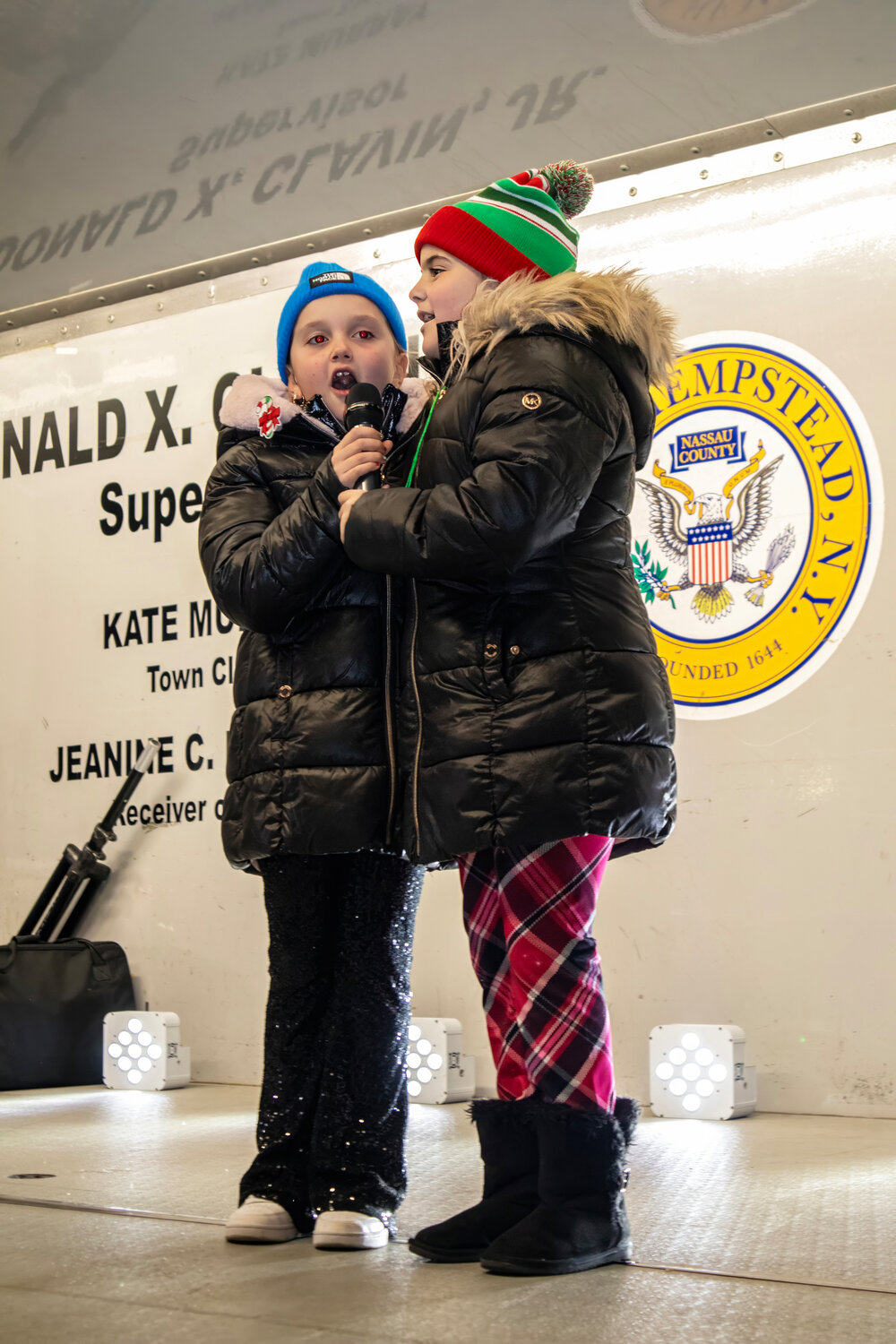 Alyssa Fratarcangeli, 8, and Mia Abreu, 8, sang a Chanukah song on stage at the Lidl shopping center for community members at the first tree lighting ceremony of the holiday season.