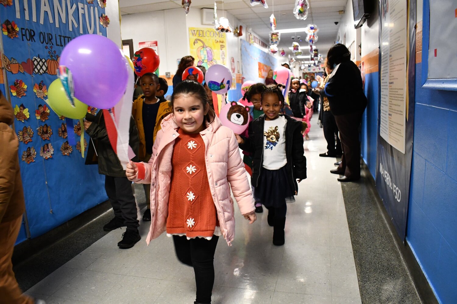 Kindergarten students march, proudly raising colorful balloons, in a celebration of the spirit of Thanksgiving.