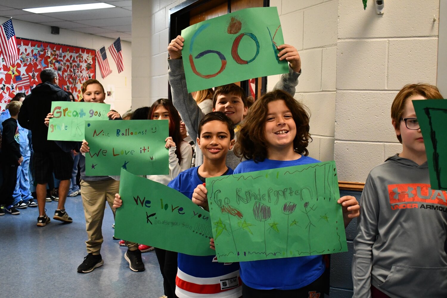 Older students beamed and cheered for the kindergarteners while holding handmade messages of support for their younger friends.