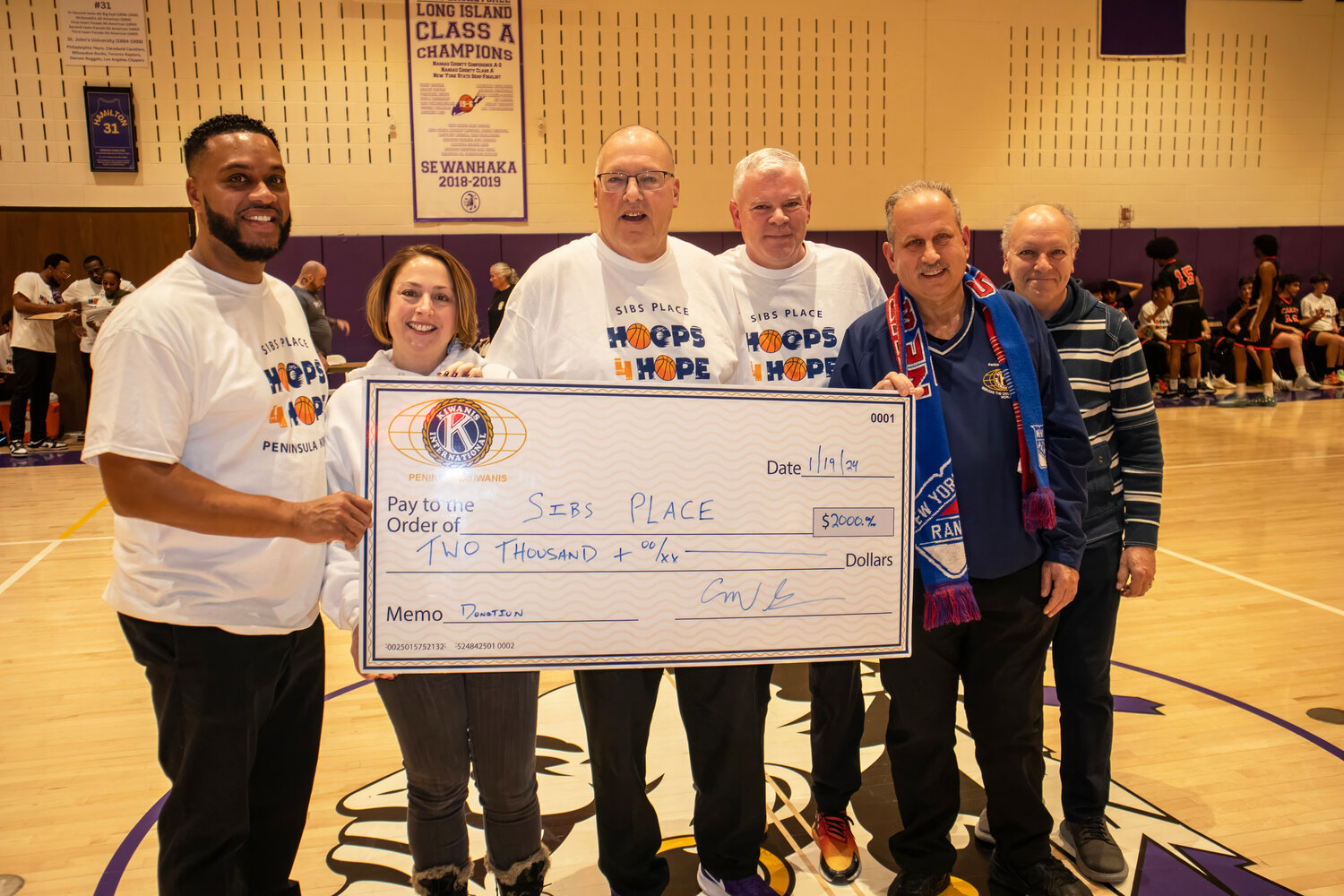Sewanhaka basketball coach Jay Allen, SIBSPlace Executive Director Joanna Formont, Sewanhaka assistant coach Bill Dubin, Carey coach Dan Reece, former SIBSPlace President Michael Gliner and its secretary, Sheldon Soloway, with a check from the Peninsula Kiwanis Club for the 19th annual Hoops for Hope fundraiser.