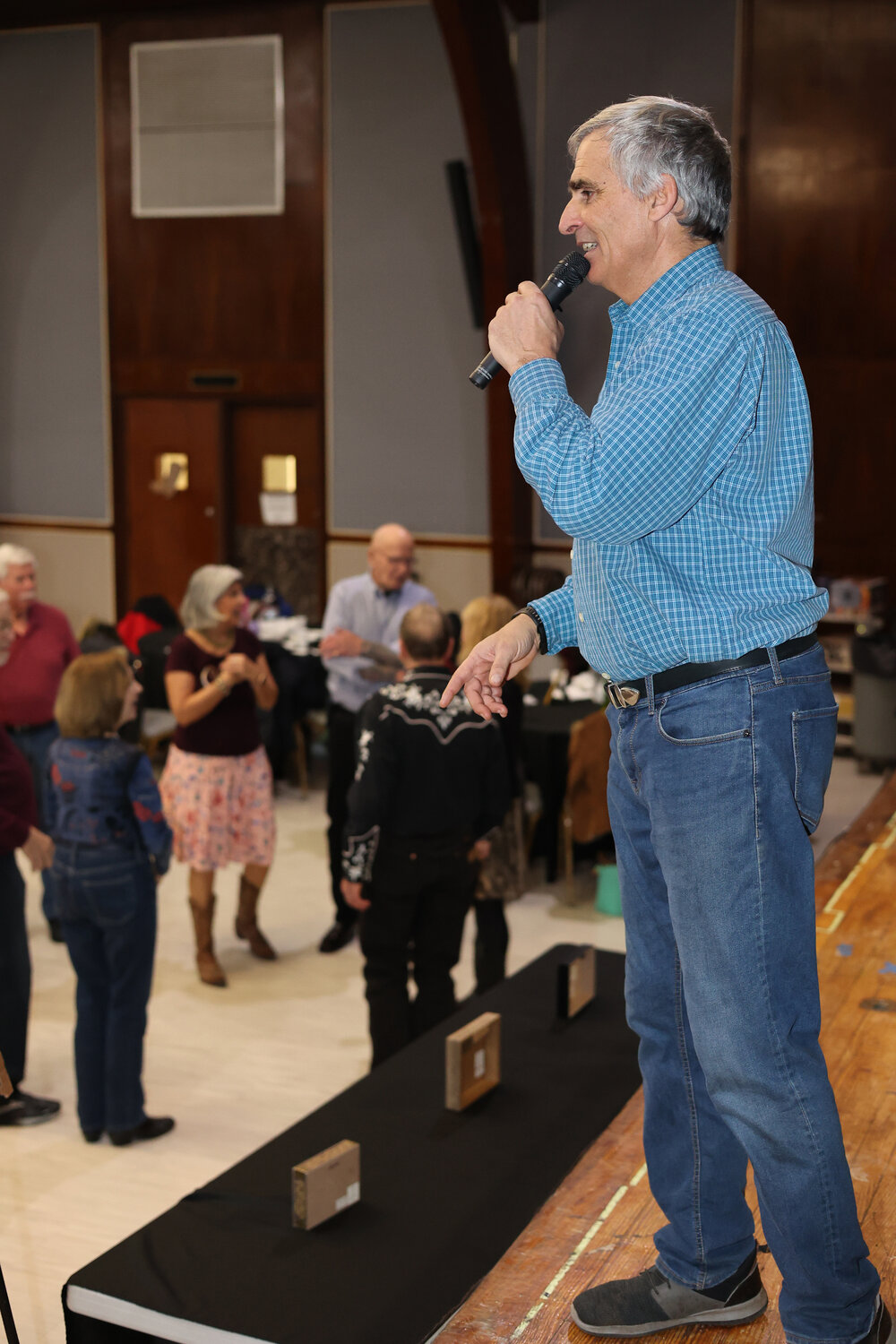 Mario Fiore, the square dance caller at the event, speaks onstage to the dancing crowd. Fiore is the son of Primo Fiore, who famously taught square dancing at the Jones Beach Bandshell.