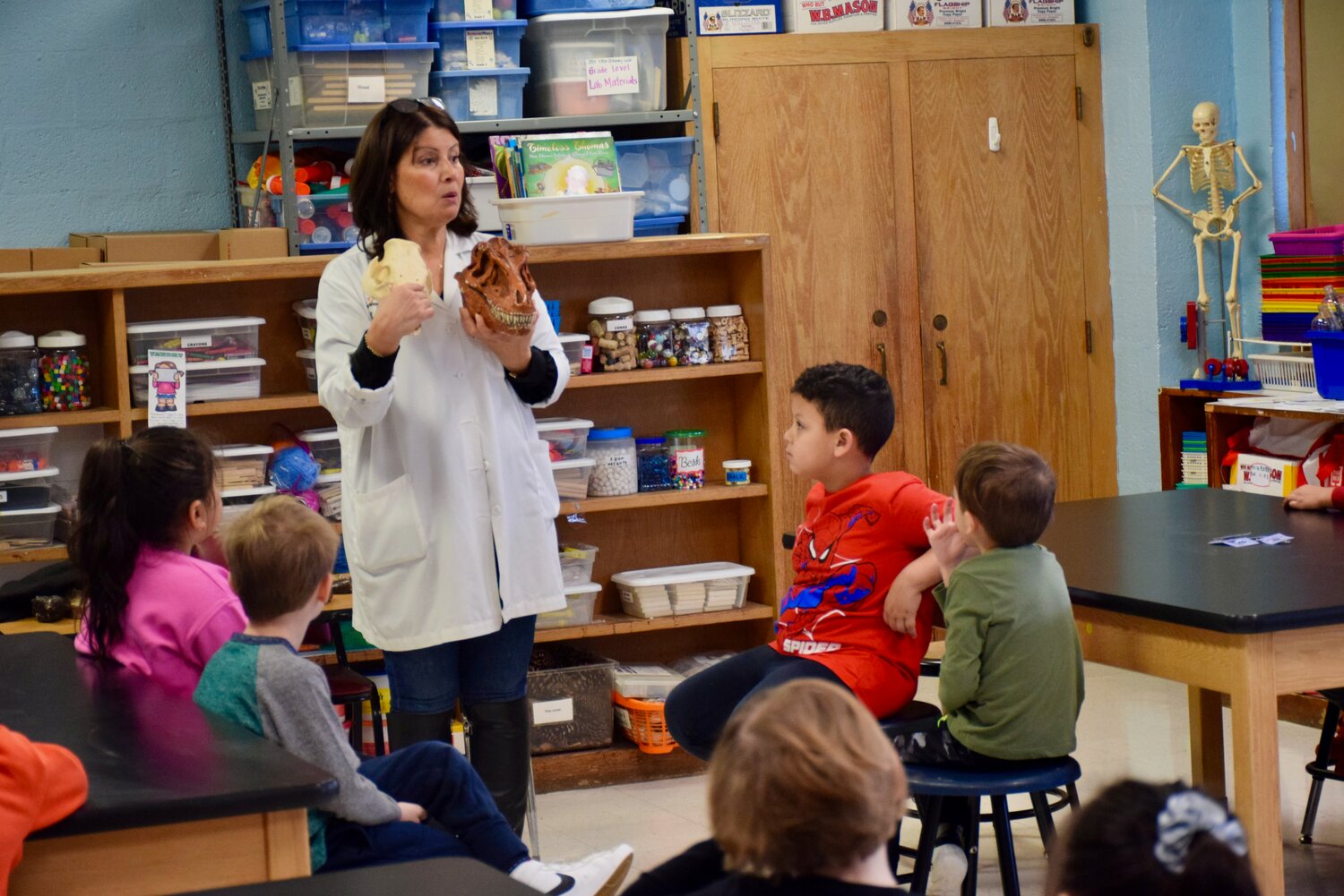 A representative from the Long Island Science Center teaches Franklin Square students about dinosaurs using replicas and fossils of dinosaur eggs, teeth and a skull.