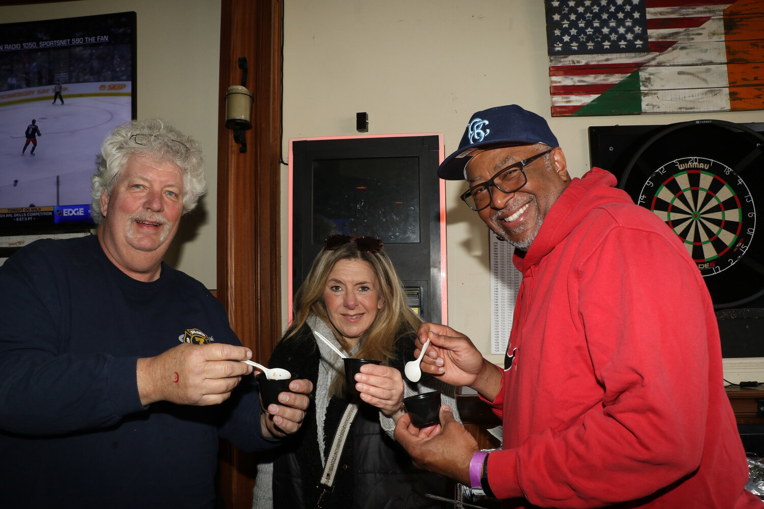 Friends John Cools, Jessica Saracco, and Chris McCleese gathering at the pub as they enjoy the warmth and taste of the chili.