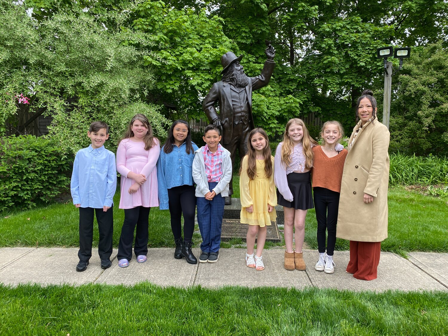 Members of the Birch Pages Writing Club in front of a statue of Walt Whitman. The club earned first place at the annual student poetry contest held by the Walt Whitman Birthplace Association.