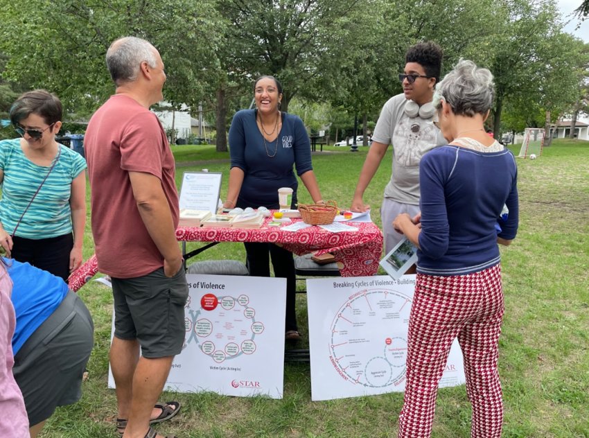 Crixell Shell of the Minnesota Peacebuilding Leadership Institute talks with community members at the Lowry Hill East Neighborhood Association's Twin Cities Community Pop-Up Market at Mueller Park on Aug. 20.