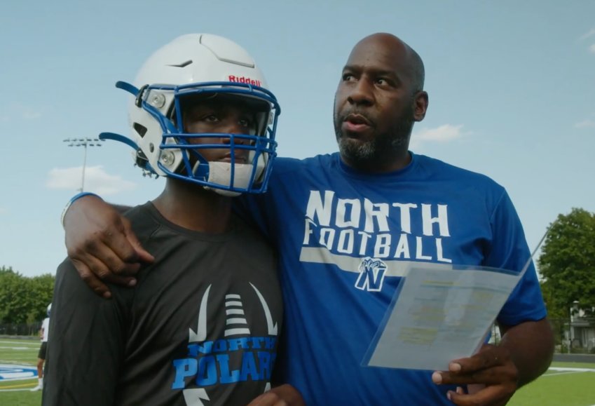 North High School assistant football coach and MPD officer Ricky Plunkett, right, talks with quarterback Deshaun Hill during the 2021 season.