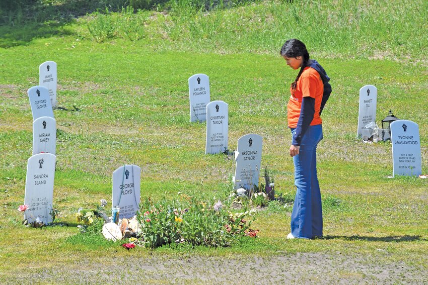 A volunteer takes a quiet moment to reflect at the Say Their Names cemetery during the Rise &amp; Remember Festival on Saturday, May 27.