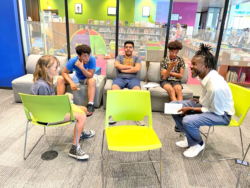 Young students work with restorative practices leader Manu Lewis during a team building exercise at the Strong Mind Strong Body Foundation’s Community Solutions With Youth workshop at Walker Library in Uptown.
