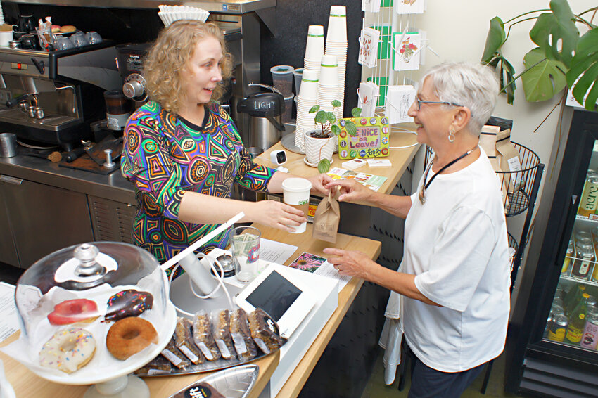 Milkweed owner Brenda Ingersoll serves Ronnie Hartman coffee and a donut as part of the Too Good To Go program that pairs customers with surplus unsold food at restaurants for lower prices.