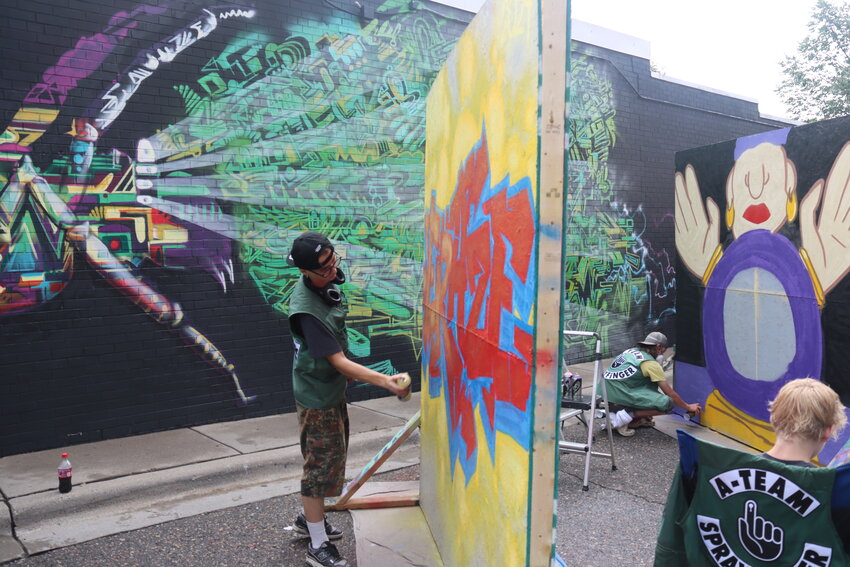 Ezra Young, 17, of Roseville works in the SPRAYFINGER area next to the Uptown VFW during the LynLake Street Art Series on Saturday, July 13, 2024. “This is not just a grubby alleyway anymore. It’s art,” Young said.  (Photo by Tesha M. Christensen)