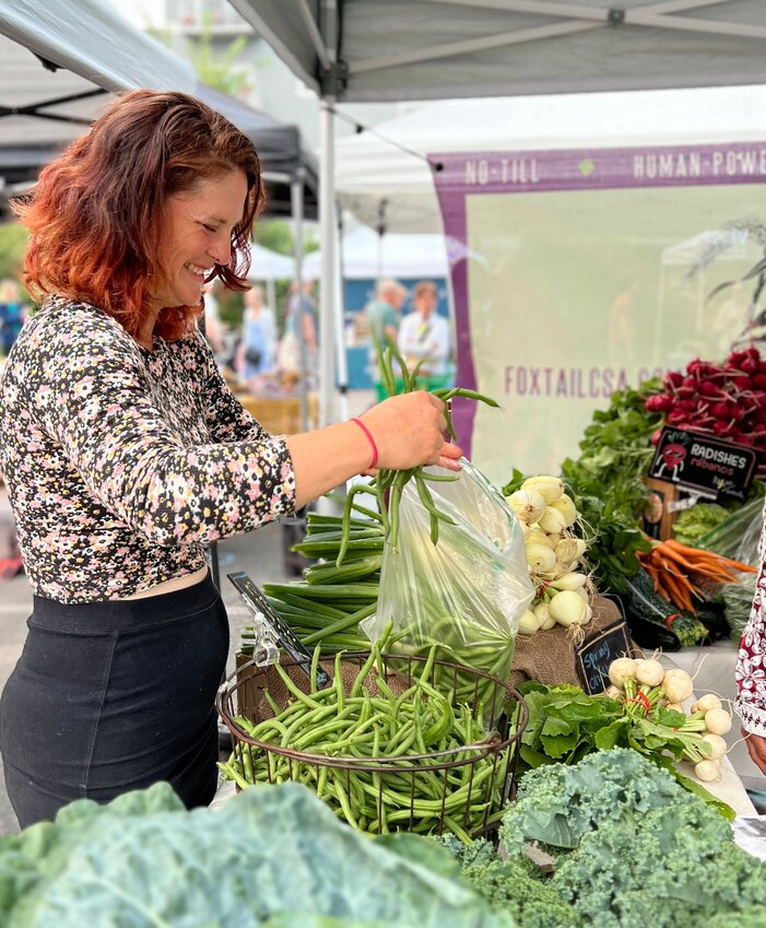 Past Neighborhood Roots board member Ashley Olson packs green beans at the Fulton Farmers Market. Starting this week, the Fulton Farmers Market will be replaced by the Southwest Farmers Market, and be located at a new location that will allow the market to double in size.  (Photo courtesy of Neighborhood Roots)