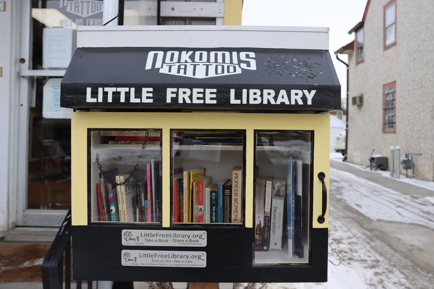 The newly created bilingual (Spanish and English) Little Free Library in front of Nokomis Tattoo.