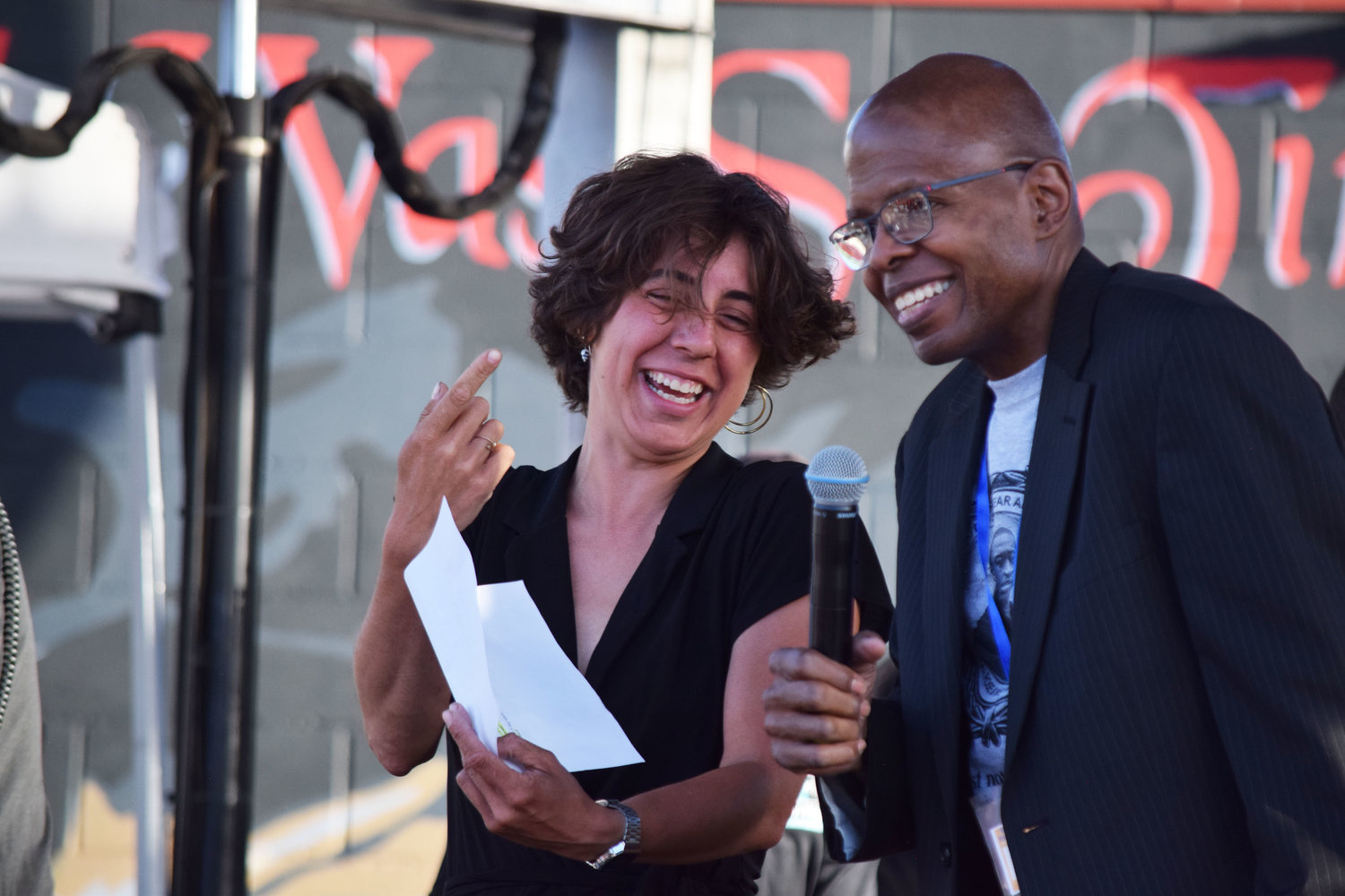 Madi Ramirez-Tentinger (at left) and Vins Harrelson share a laugh as emcees for the Concert Honoring Families of Injustice or Loss at the Rise & Remember event on May 25th at George Floyd Square.