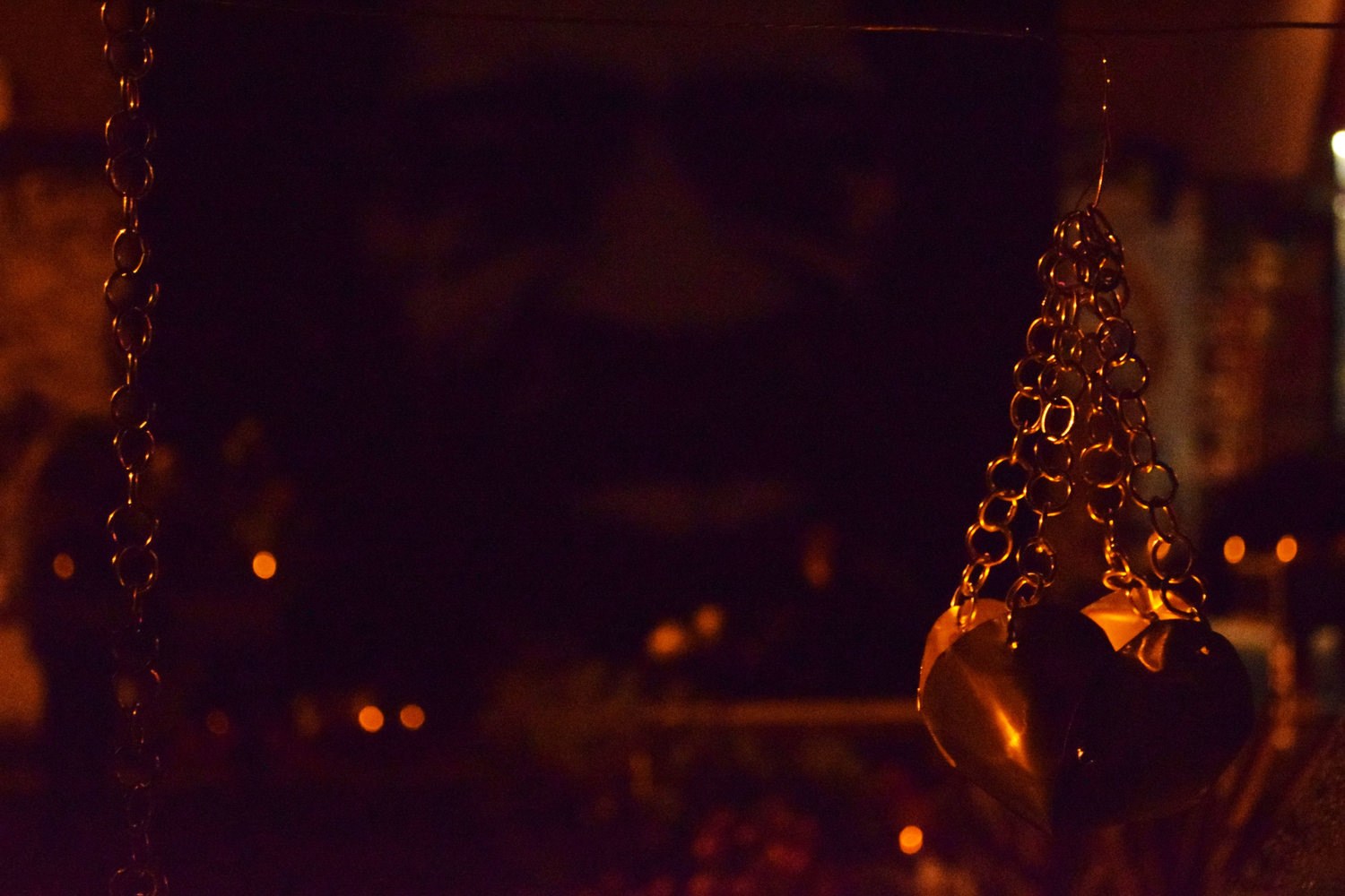 A candle lights a heart-shaped luminary suspended from a metal chain in front of George Floyd’s portrait.