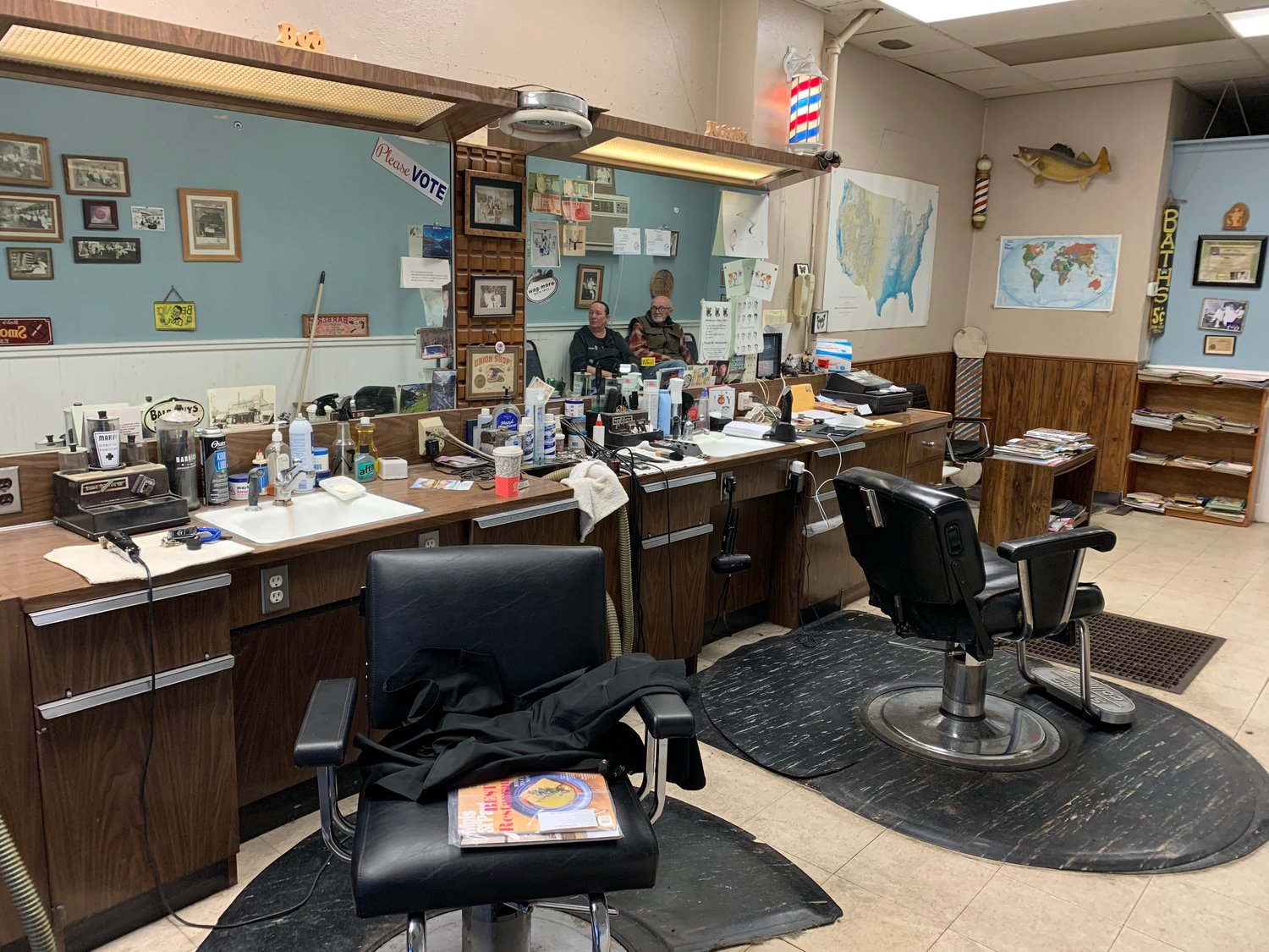 Barbers Bob Ohnstad and daughter Kristin Ohnstad are reflected in the mirror of the barbershop they’ve operated since 1993.