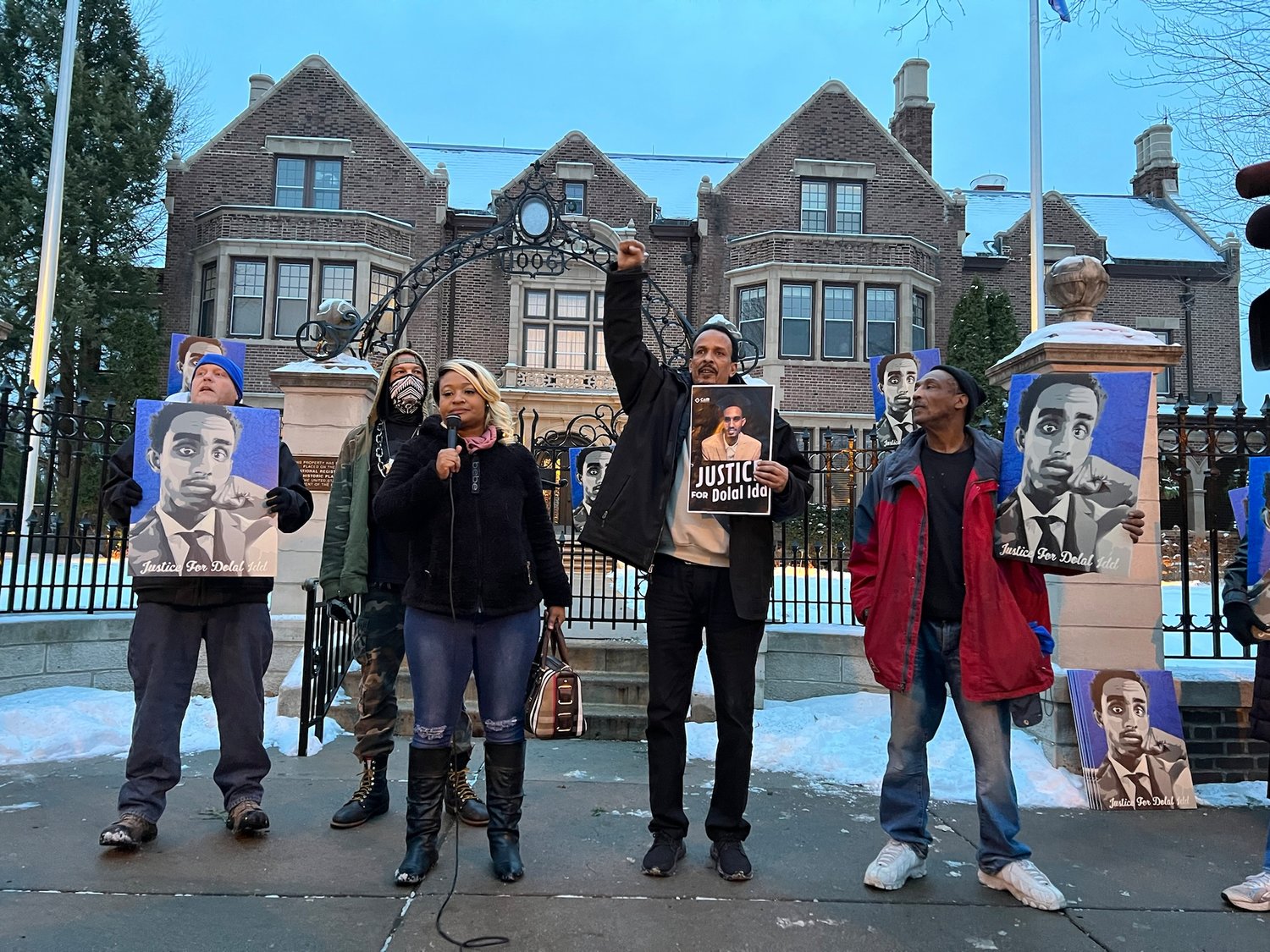 Toshira Garraway Allen speaks on Jan. 4, 2022. Bayle Gelle, Dolal Idd’s father, stands next to her, fist raised. Demonstrators marched from Summit Ave. to Grand Ave., around the governor’s residence and back.