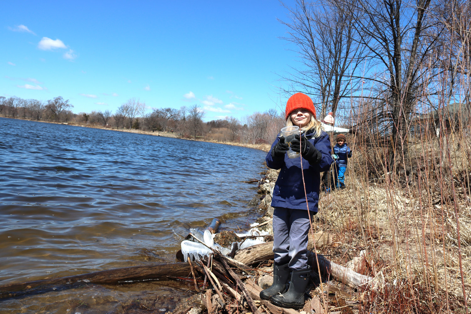 Weston Cavender, 6, picks up trash and explores along the shore of Lake Hiawatha near the recreation center. The golf course property is seen in the background.