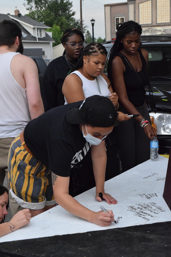Community members sign the base of the fist. (Photo by Jill Boogren)