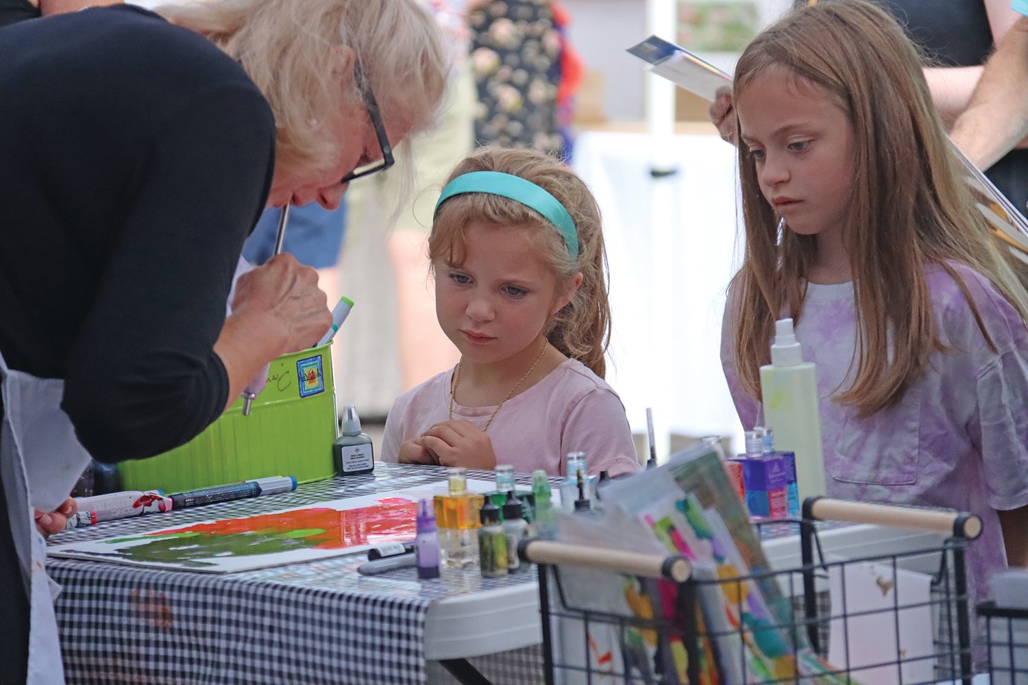 Lucy Duncan, age 5, and her sister Lydia, age 8, watch soul painter Anne Pryor of Lovitude at work during Art on the Edge. They were accompanied by grandmother Beth LaVal (not pictured.)