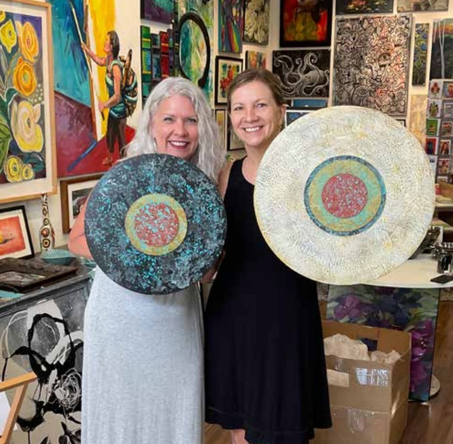 Suzie Marty (left) and Jodi Reeb hold up two of her mixed-media artworks at Everett & Charlie art gallery in Linden Hills. Reeb said, “The focus of my artwork has always been about the magnificence and beauty of nature, and finding inspiration from nature’s extraordinary colors and light.