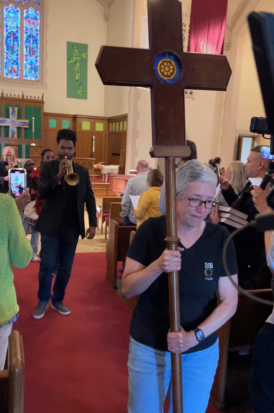 Shari Seifert, carrying the processional cross at the end of the service on September 11, sees the project to bring deeply affordable housing to 39th and Chicago as demonstrating “tremendous care for neighbor.” Behind her, Butchy Austin leads Brass Solidarity down the aisle.