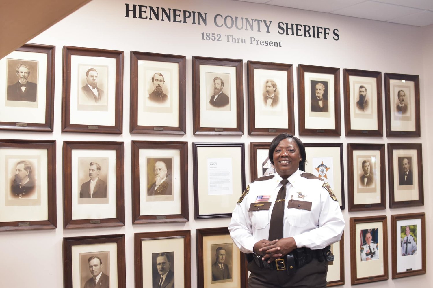 Dawanna Witt stands next to photos of the 28 White men who preceeded her as Hennepin County Sheriff.