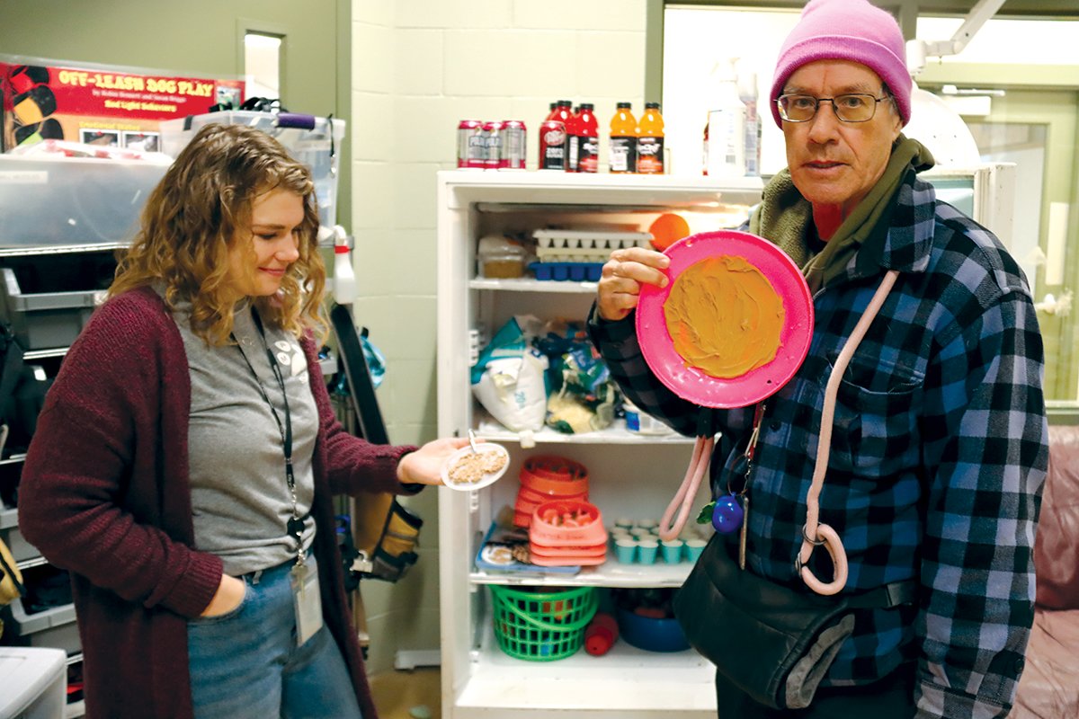 Madison Weissenborn (left) and Lyle James hold up small and large frisbees smeared with peanut butter that are used as treats and enrichment.