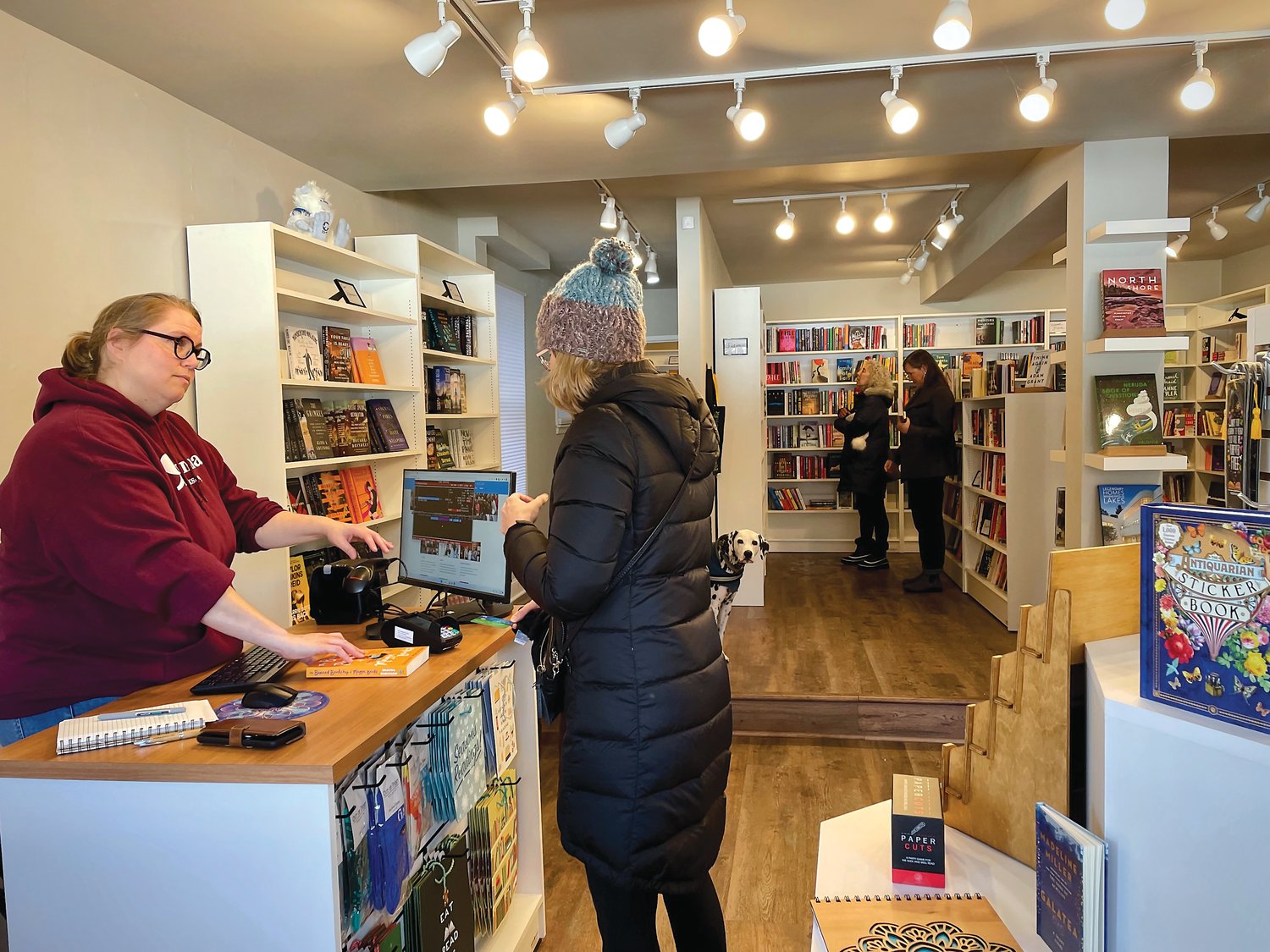Victoria Ford, proprietor of the new Comma Bookshop in Linden Hills, consults with a customer. (Photo by Susan Schaefer)