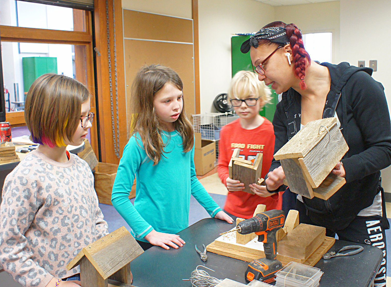 How do you make a birdfeeder? Students from Lake Harriet Community School Upper Campus build their own from reclaimed wood on Thursday, Feb. 9, 2023. Elpis  Community Programs Coordinator LaShay DeClerq-Ransom explains the drilling-the-hanger-wire-hole stage of birdfeeder construction as (left to right) Izzy Spallino, Kennedy Kaplan, and Atticus Donald watch. They also learned about the importance of birds in the environment and how to identify birds. (Photo by Terry Faust)