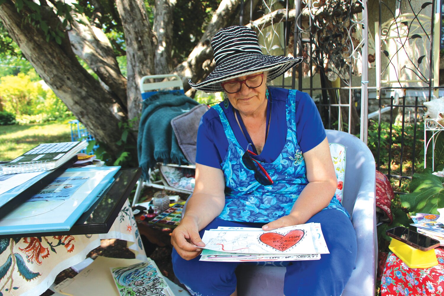 Anita White sits outside of her house, the “Amaranth Studio,” flipping through drawings she’s made over the years, of everyday life moments, including one of the four wedding rings she’s had and lost over the years. She made the drawing because she felt her husband telling her it was time to take off her wedding ring and move forward.