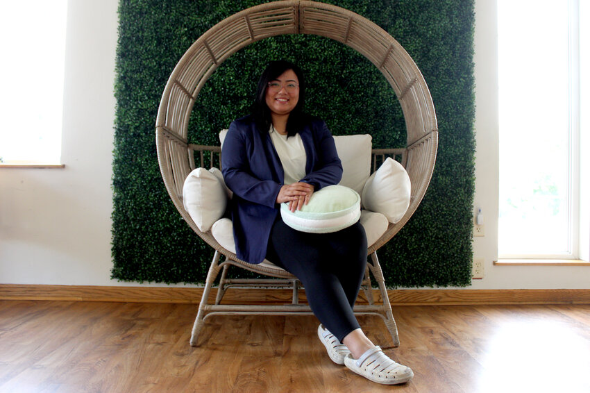Alanna Thao poses in a chair with one of her macaron cookie pillows at her The Moonlit Bakery business. The spot at 1720 Merrill Ave. in Wausau is part of a wave of recent bakery openings.