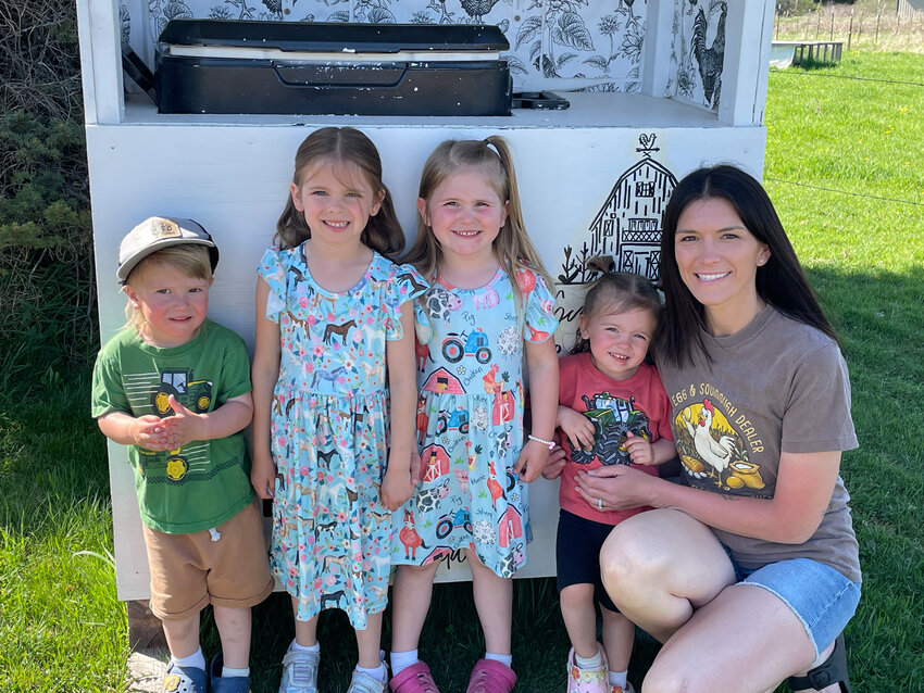 Katie Sczygelski with her four children—ages 6, 4, and 2-year-old twins—pose by their Sczygelski Farm Products market stand at their property on Fairview Rd.