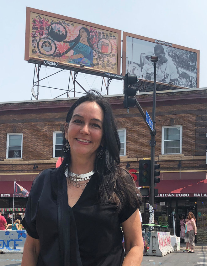 Tina Tavera stands with her billboard &ldquo;La Conneccion&rdquo; on the Cup Foods rooftop behind her. (Photo by Jill Boogren)