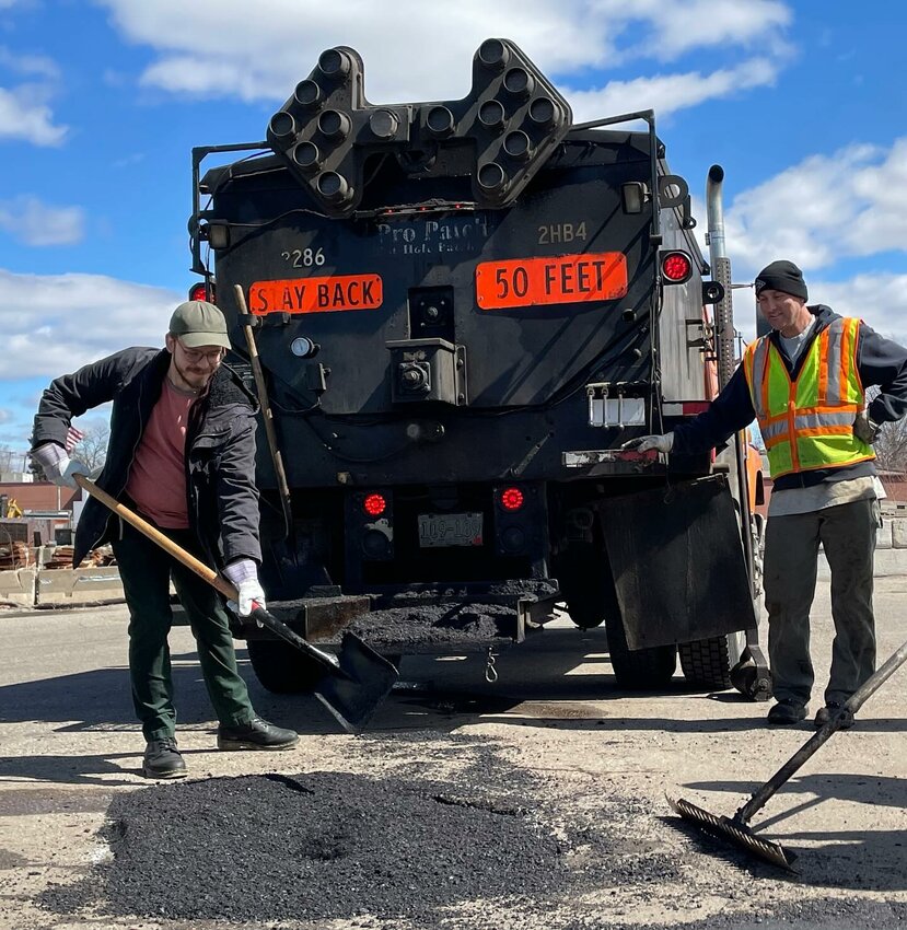 Hamline student Ben Rosenberg (left) shovels asphalt at the St. Paul Asphalt Plant.