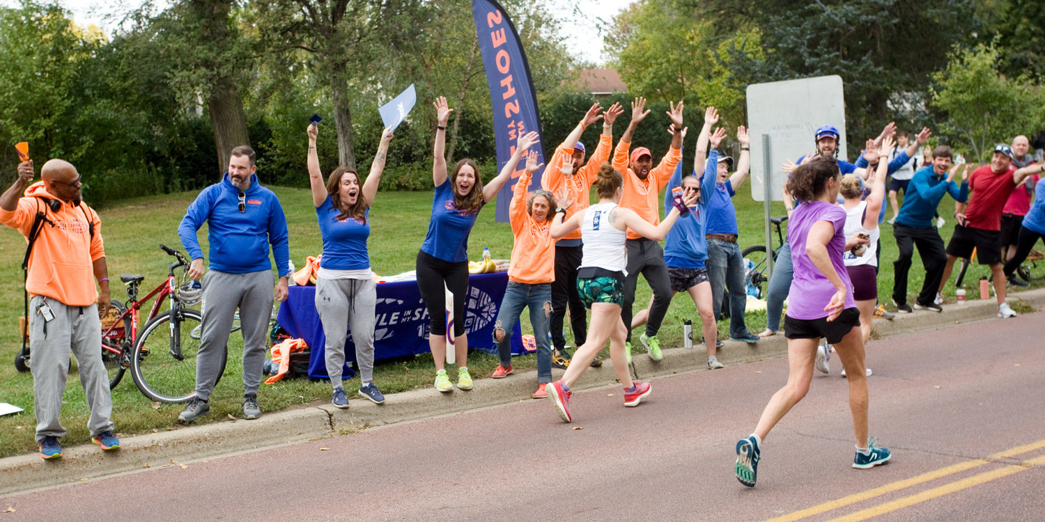 MiMS members cheered on the Twin Cities Marathon at mile 17 along the course on Sunday, Oct. 3. Co-founder and director Mishka Vertin (fourth from left), said, “We never intended for this to become big. We just wanted to start one little team. This year seven of our runners competed in the marathon.” (Photo by Margie O’Loughlin)