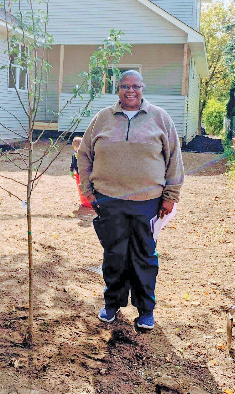 A Frogtown homeowner and her new tree, planted by one of the “Tree Frogs” last year.
