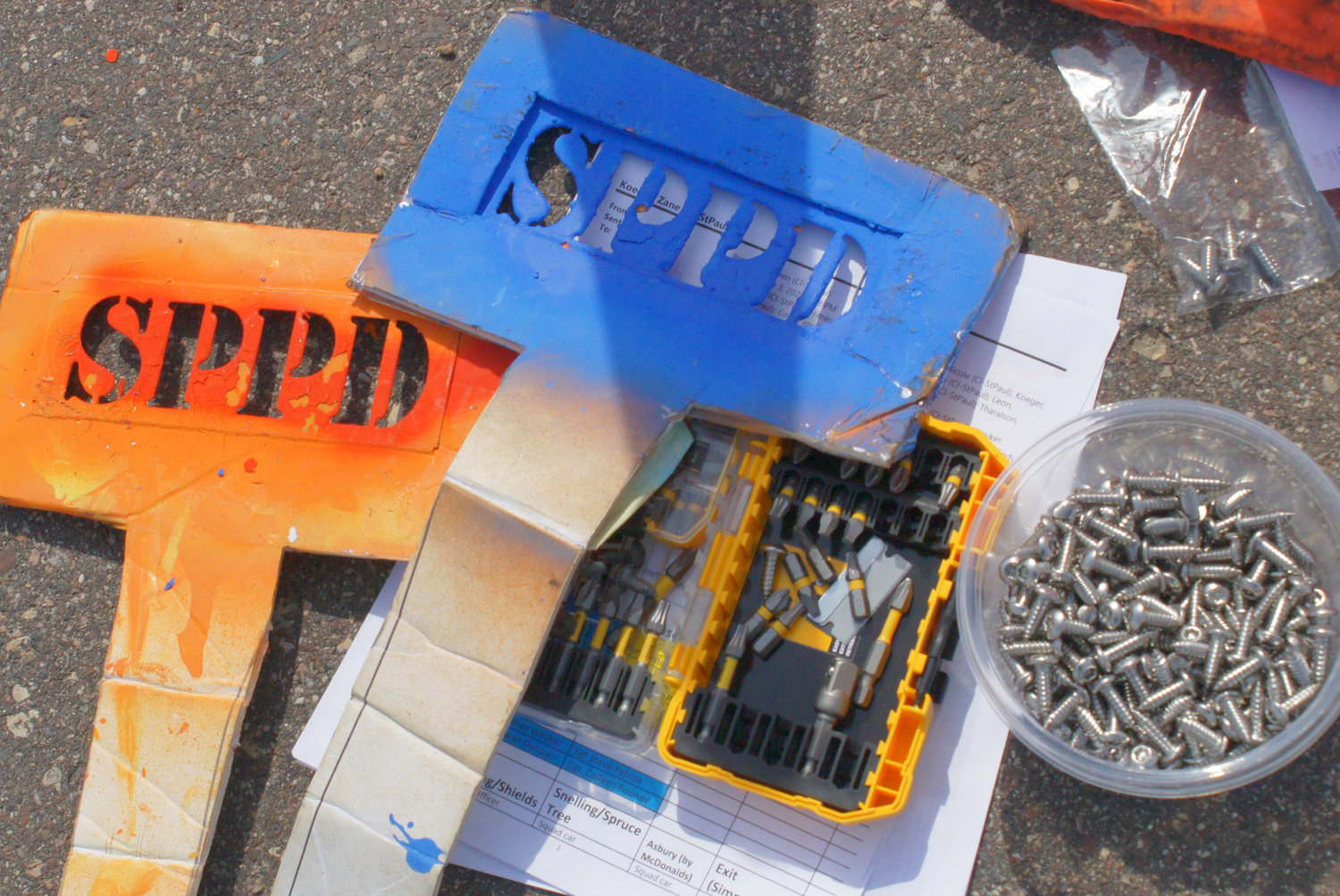 Tools of the event: SPPD stencils were placed against converters before painting when vehicles had high ground clearance. A variety of screw bits were used for the drills to replace existing license plate fasteners with anti-theft screws.