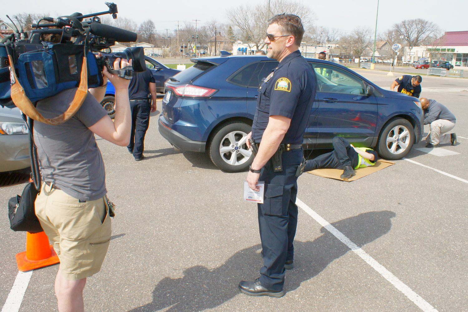 Sr. Commander Hallstrom explains the operation to a news crew while a “pit crew” paints a converter and installs anti-theft license plate screws.