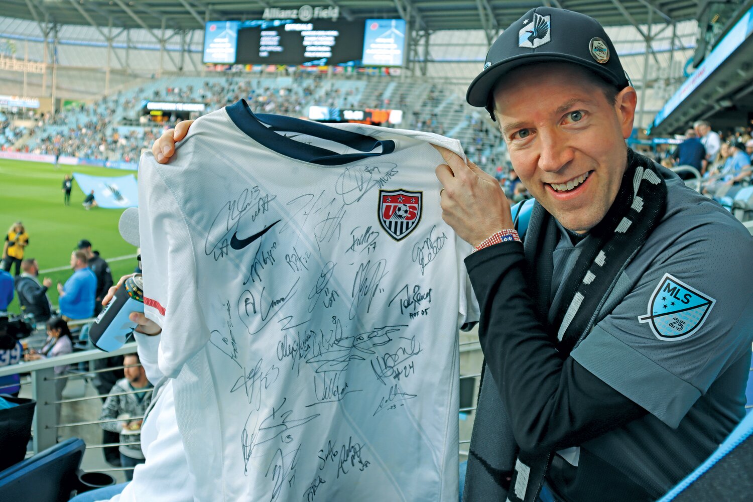 Season ticket holder Jericho Tabor of Minneapolis holds up a jersey with collected signatures from U.S. National team players during a May 2023 Loons game.