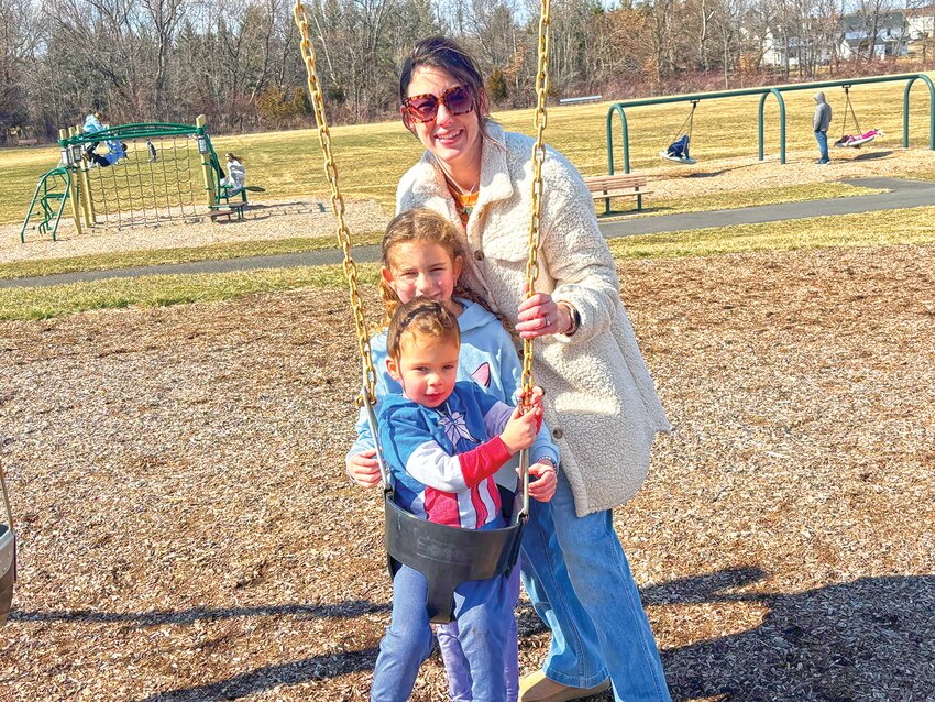 Megan Wolf (mom) and daughter Norah, enjoy pushing Wyatt on the swing at the Recreation Station Playground.