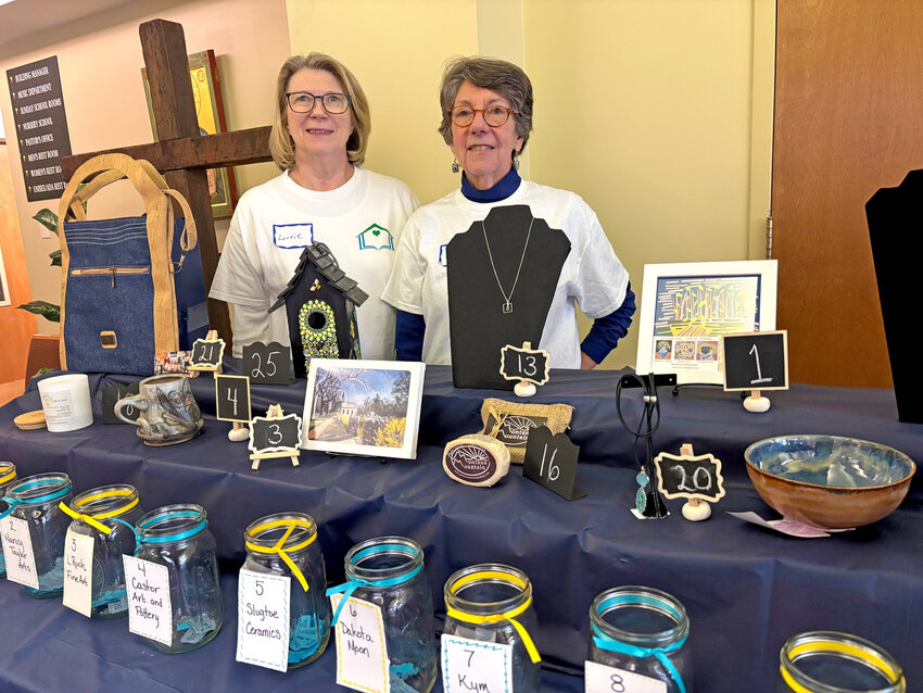 Cochairs of Crafts Fair, Lorrie Richardson (left) and Donna Tobin, stand behind the raffle table.