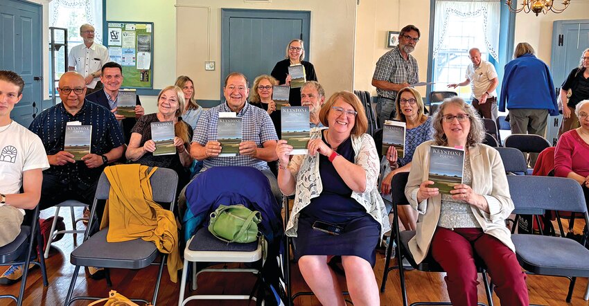 Attendees and poets hold up their copies of “Keystone Poetry: Contemporary Poets of Pennsylvania”.