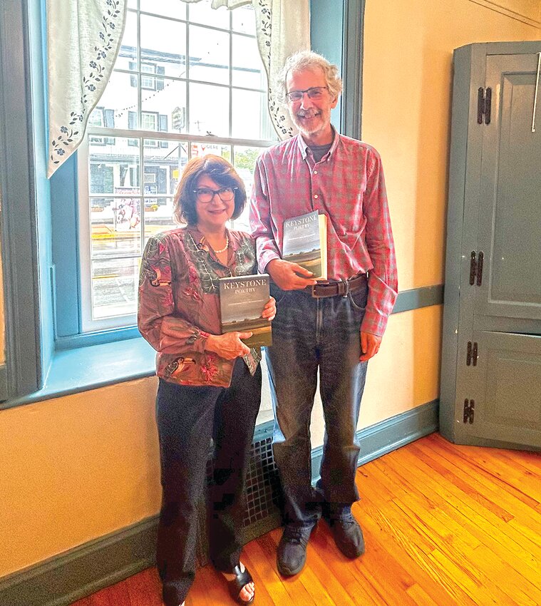 Attendees and poets hold up their copies of “Keystone Poetry: Contemporary Poets of Pennsylvania”.