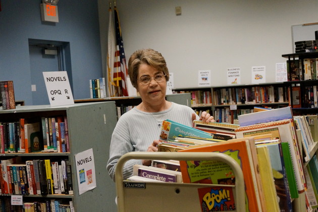 Ginnie Hogan, Friends volunteer, stocks some of the thousands of gently used books that will be selling at very reasonable prices at the Fall Book Sale at East Providence&rsquo;s Weaver Library October 19-22.