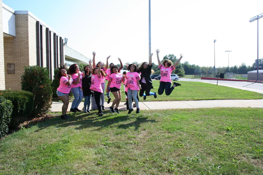 Juniors and seniors jumping to get ready for the walk for breast cancer.