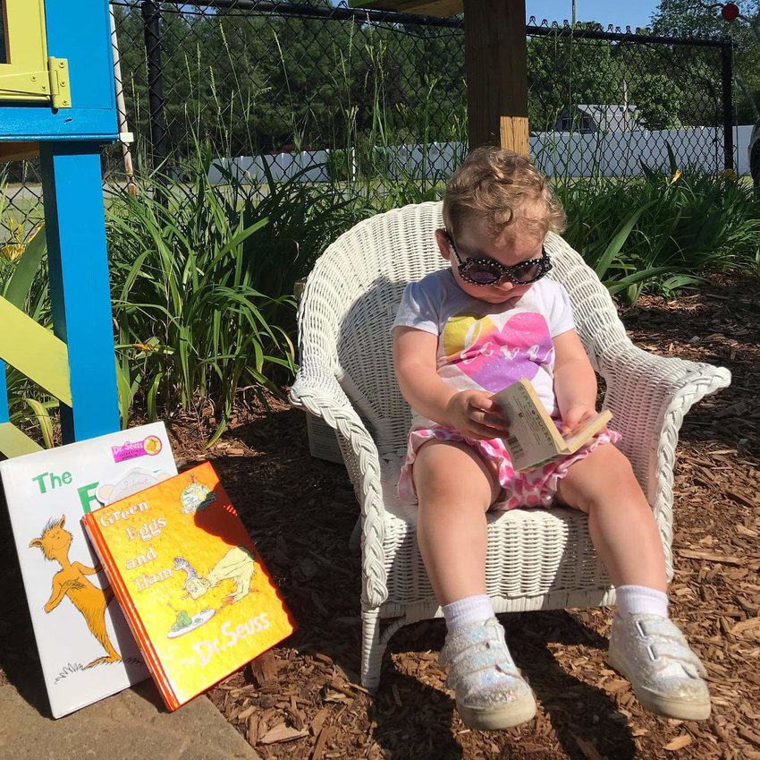 14 month old Cora Timberlake came with her mother, Amanda Timberlake, to donate two Dr. SEUSS books and take advantage of a &quot;photo op&quot; with a good book at our Little Free Library.