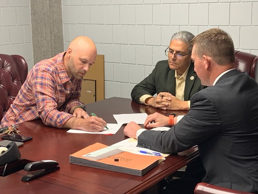 Ruarri Miller, a Riverside resident and owner of the Union Bar, signs closing documents after being approved for a loan in the amount of $99,999 by the East Providence Economic Development Commission.
