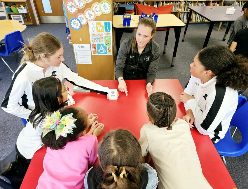 Members of the Providence College Women&rsquo;s Soccer Team lead a math activity with students from Orlo Avenue Elementary School&rsquo;s afterschool program in partnership with the Boys &amp; Girls Club of East Providence. Pictured from left to right: Providence College Women&rsquo;s Soccer Team Member Gillian Kenney, Providence College Women's Soccer Assistant Coach Katie Day and Providence College Women&rsquo;s Soccer Team Member Naiya McFarlane and Orlo Avenue Elementary School students.