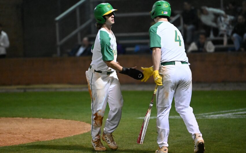 Senior Landon Taylor (left) high-fives senior Riley Brown (4) after scoring on a double steal in the sixth inning Friday.